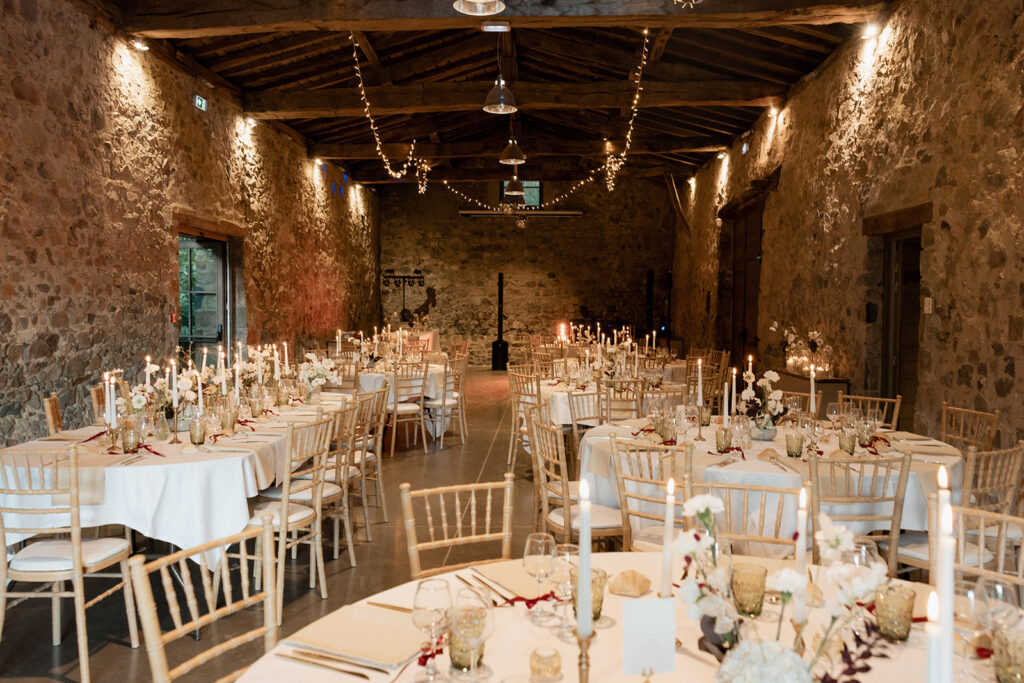 Salle de réception en pierre dressée pour un dîner de mariage aux chandelles